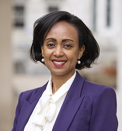 A headshot of Lia Tadesse Gebremedhin. She is wearing a purple blazer over a white blouse.